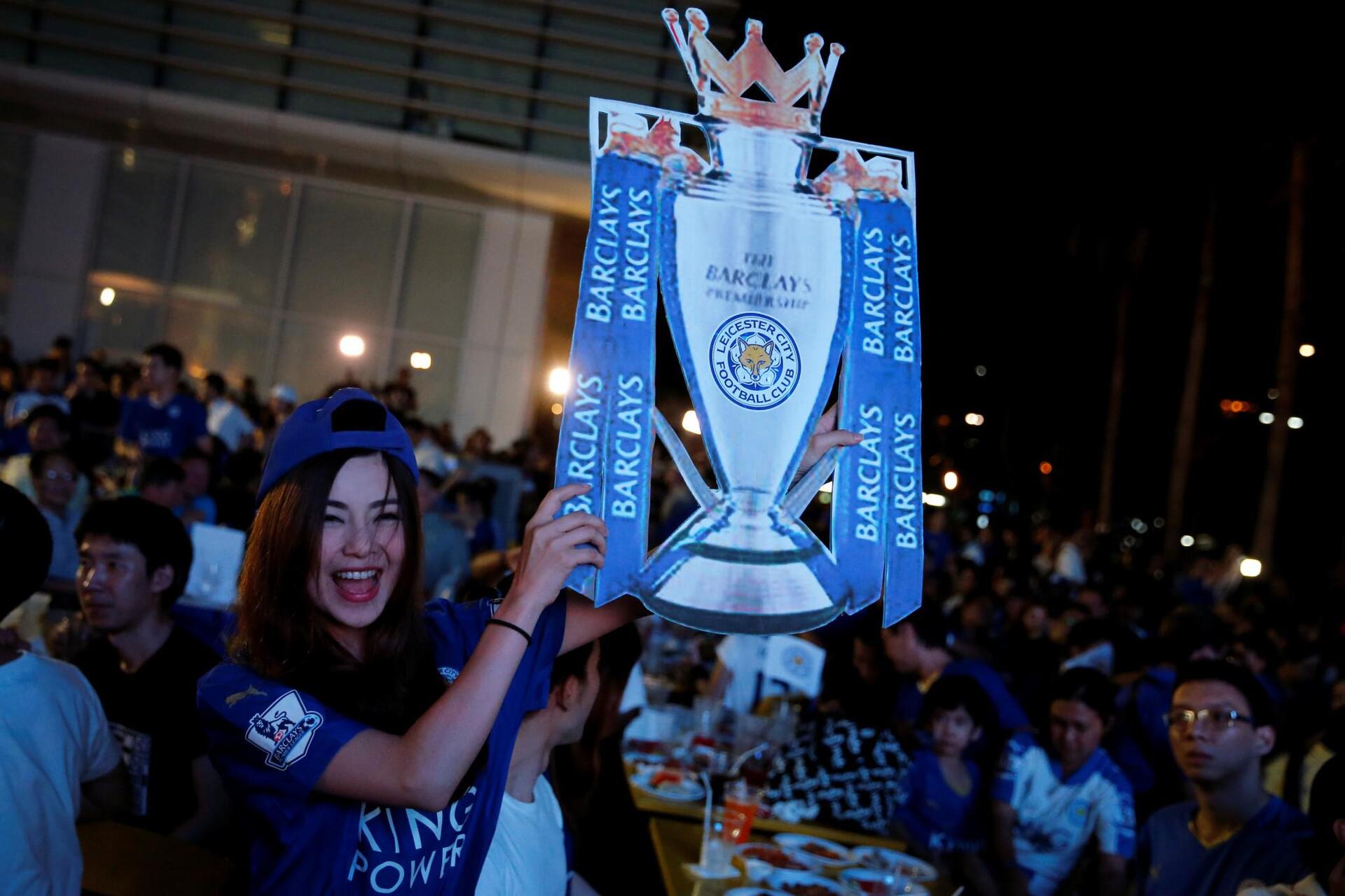 Leicester City fans celebrate after their team drew against Manchester United while watching the game on a big screen in Bangkok
