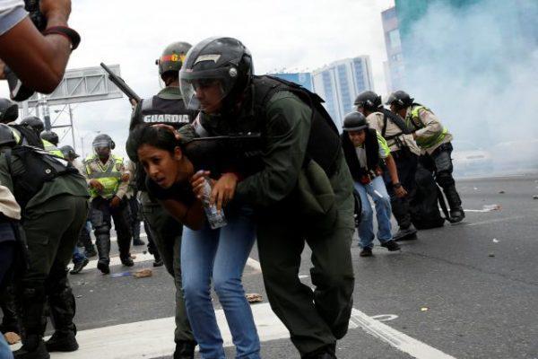 A Venezuelan National Guard covers a woman as they run away from tear gas during a rally to demand a referendum to remove President Nicolas Maduro in Caracas, Venezuela, June 7, 2016. REUTERS/Carlos Garcia Rawlins