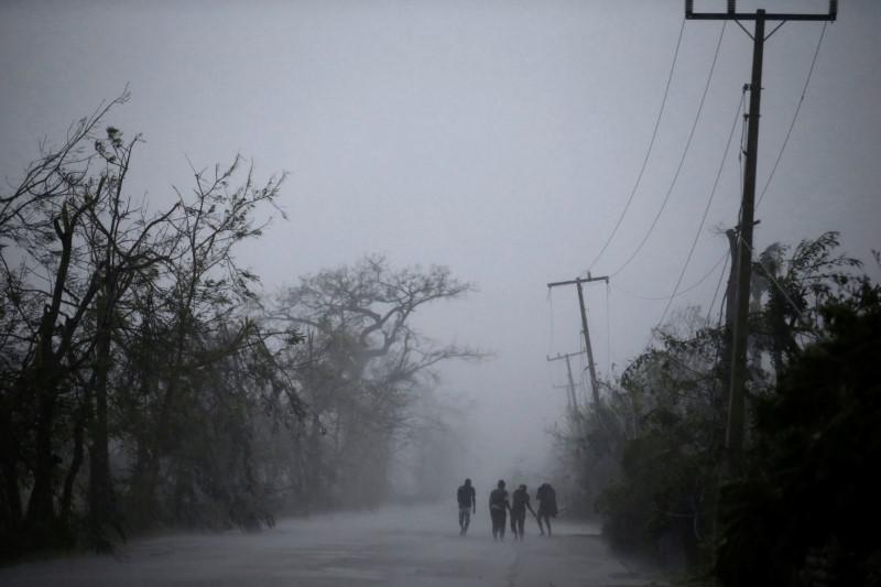 People walk on the road as rain falls during Hurricane Matthew in Les Cayes, Haiti, October 4, 2016. REUTERS/Andres Martinez Casares