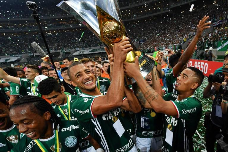 Palmeiras player Gabriel Jesus (R) holds up the trophy as he celebrates with teammates after winning the Brazilian championship football final match against Chapecoense and becoming champions at Allianz Parque stadium in Sao Paulo Brazil on November 27 2016. / AFP PHOTO / NELSON ALMEIDA