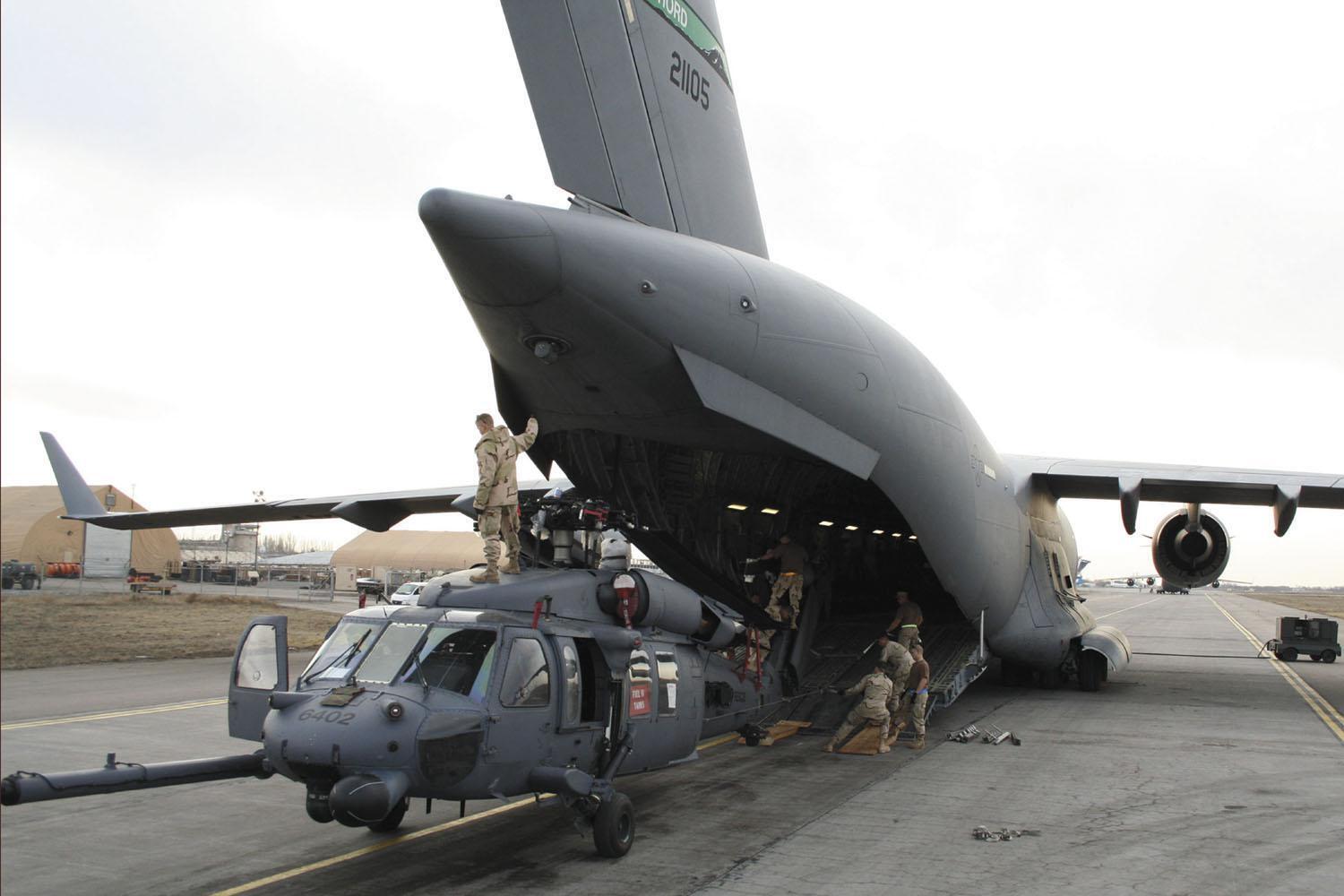 Air Force Reserve aerial porters work with maintainers to load a UH-60L Blackhawk rescue helicopter into a C-17 Globemaster III at Manas Air Base, Kyrgyzstan.